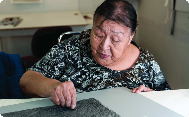 Inuit artist working on piece of artwork.